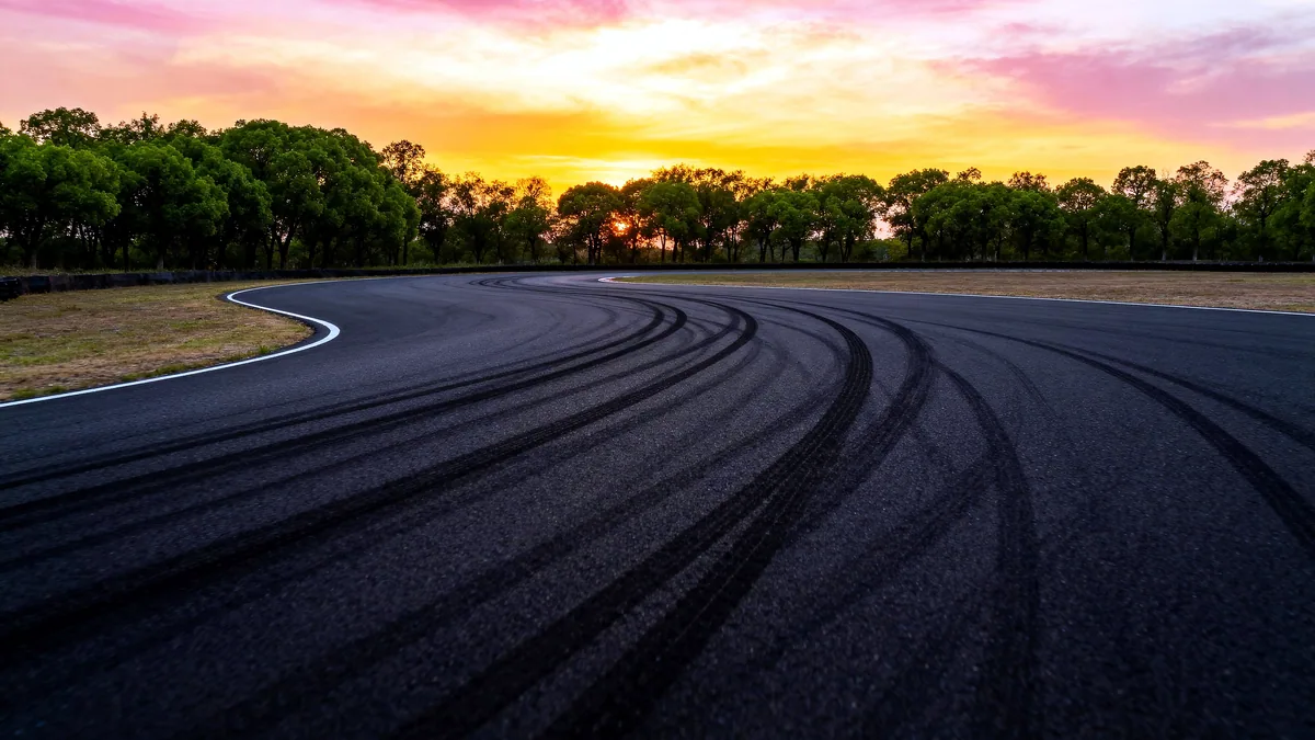 An empty racetrack curving into the distance under a wide open sky at dusk.